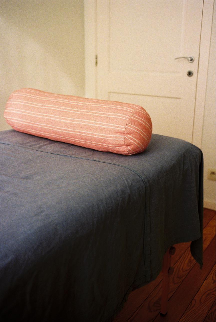 Coussin rayé posé sur la table de massage, drap bleu